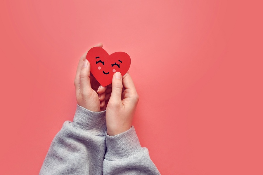 A,Red,Paper,Smiling,Heart,In,The,Hands,Of,A