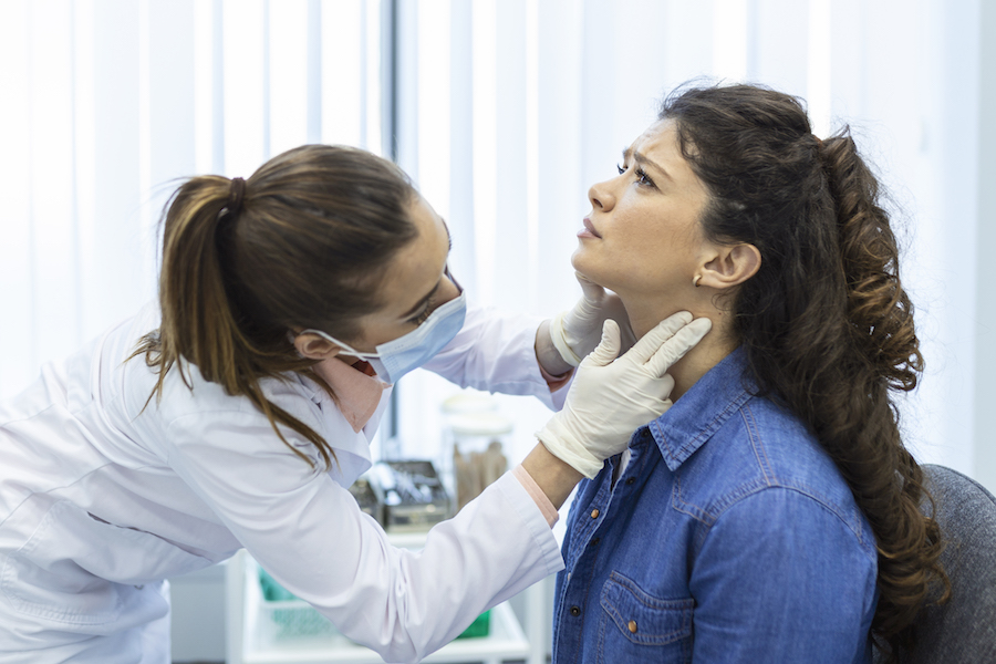 Endocrinologist examining throat of young woman in clinic. Women with thyroid gland test . Endocrinology, hormones and treatment. Inflammation of the sore throat
